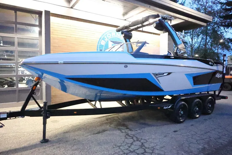 Slide: The Image of 2022 Tigé 24RZX boat on trailer, parked outside a building at dusk. - 58