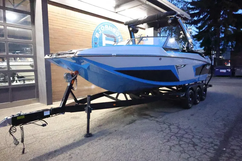 Slide: The Image of 2022 Tigé 24RZX boat on trailer, parked outside a building at dusk. - 59