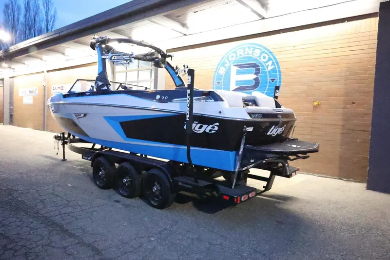 Slide: The Image of 2022 Tigé 24RZX boat on trailer, parked outside a building at dusk. - 60
