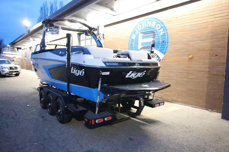 Slide: The Image of 2022 Tigé 24RZX boat on trailer, parked outside a building at dusk. - 61