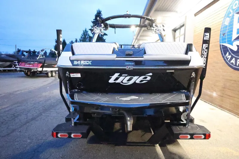 Slide: The Image of 2022 Tigé 24RZX boat rear view at marina, showcasing sleek design and branding. - 62