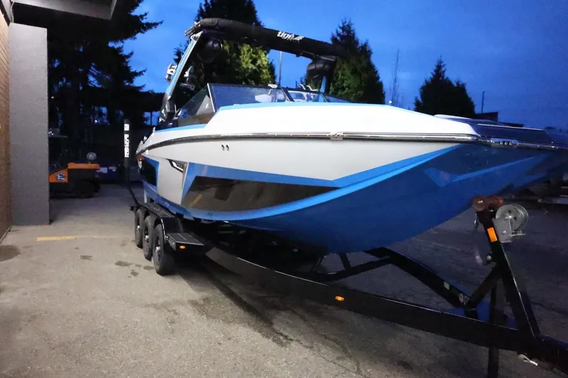 Slide: The Image of 2022 Tigé 24RZX boat on trailer at dusk, showcasing sleek design and vibrant blue accents. - 64
