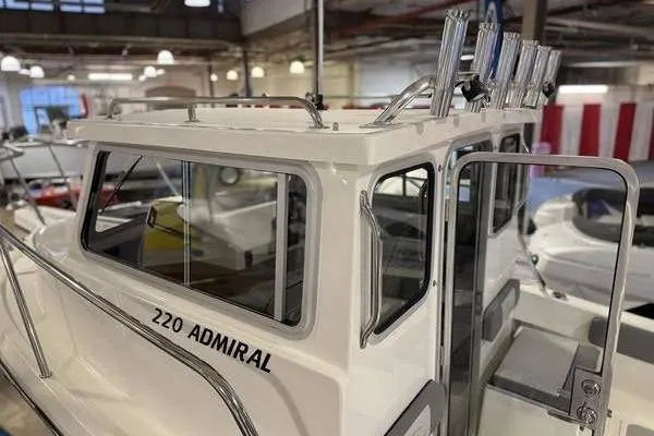 Slide: The Image of 2025 Defiance Admiral 220 EX boat in showroom, featuring sleek cabin design. - 2