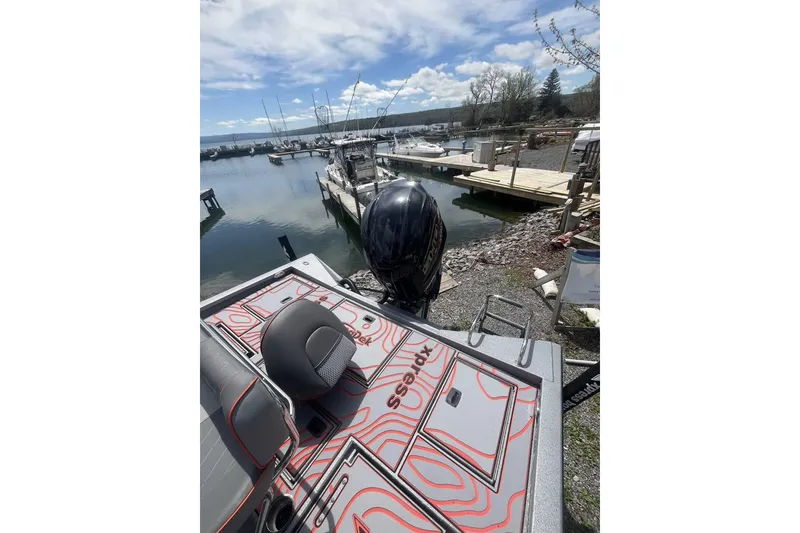 Slide: The Image of 2025 Xpress X23B Bay Lounge boat docked at a marina under a partly cloudy sky. - 4
