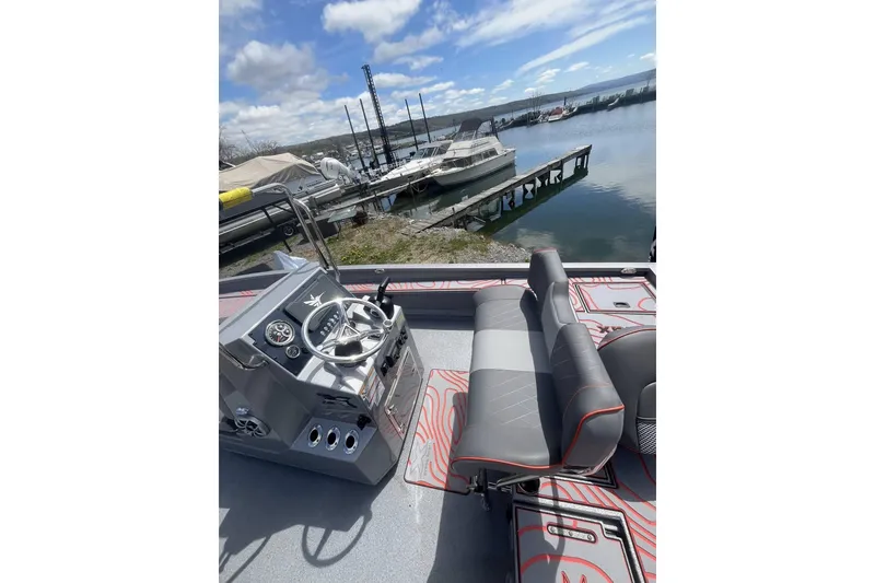 Slide: The Image of 2025 Xpress X23B Bay Lounge boat interior with steering console and seating, docked by a marina. - 7