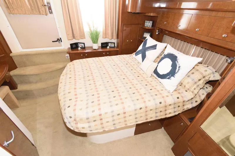 Slide: The Image of 2007 Carver 43 Motor Yacht bedroom with cozy bed, decorative pillows, and wooden cabinetry. - 24