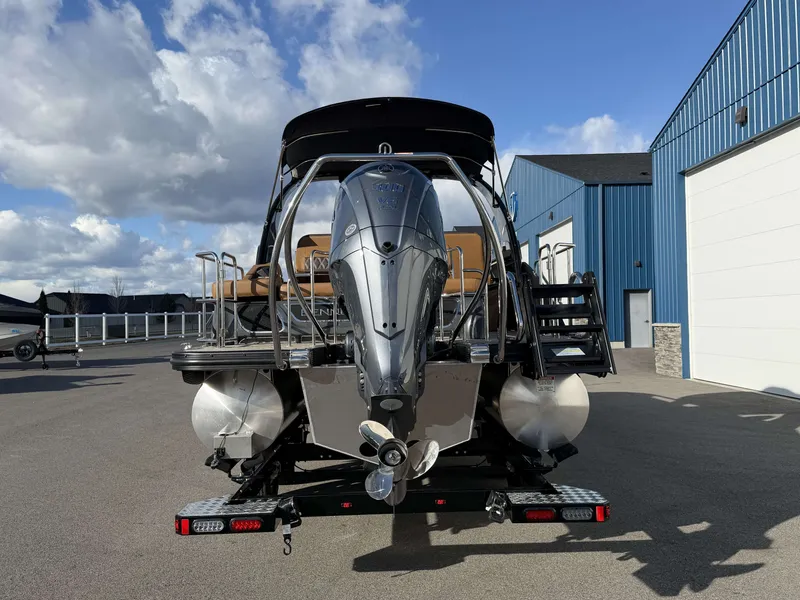 Slide: The Image of Rear view of a 2026 Bennington 25 RTSBA boat in front of a blue building. - 22