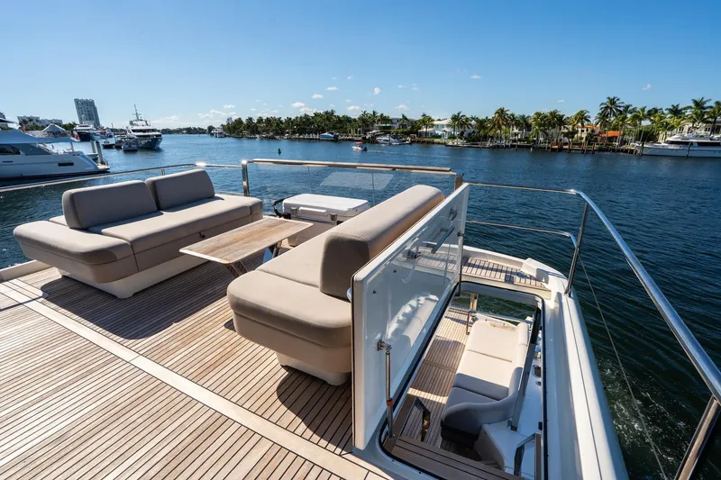 Slide: The Image of Luxury 2022 Prestige X70 yacht deck with seating, overlooking serene waterfront and palm trees. - 22