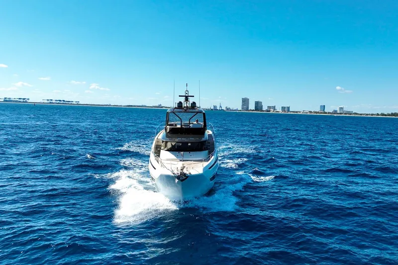 Slide: The Image of Luxury 2022 Prestige X70 yacht cruising on open blue sea near city skyline. - 6