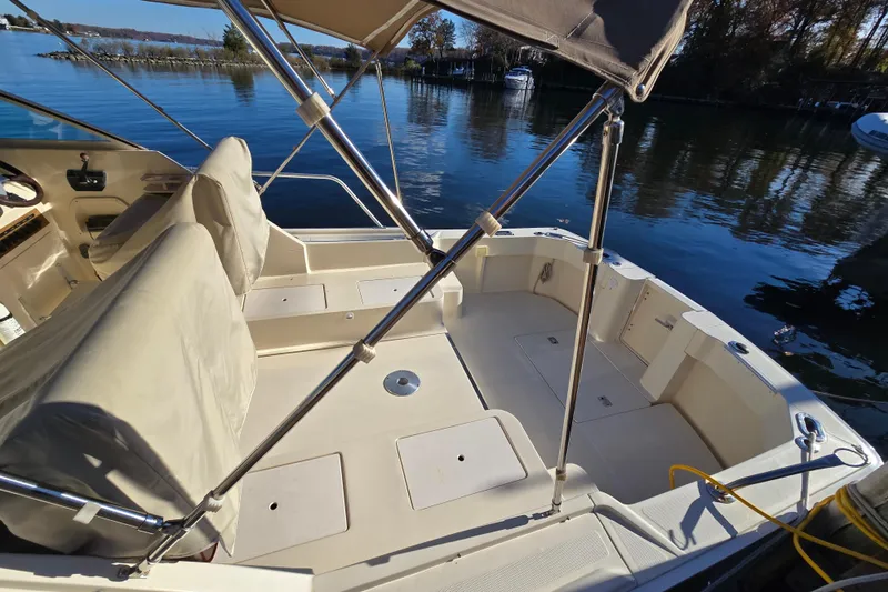 Slide: The Image of 2001 Mainship 30 Pilot Rum Runner boat interior with covered seats and calm water backdrop. - 10