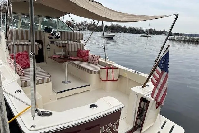 Slide: The Image of 2001 Mainship 30 Pilot Rum Runner boat with striped seating and canopy on calm water. - 13