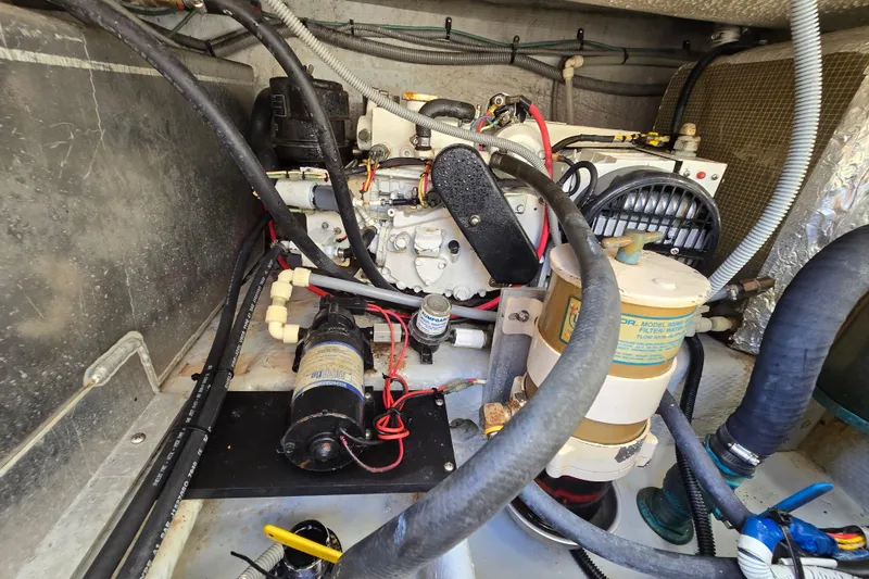 Slide: The Image of Engine compartment of a 2001 Mainship 30 Pilot Rum Runner, showcasing mechanical components and wiring. - 18