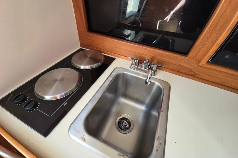 Slide: The Image of Compact kitchen area in 2001 Mainship 30 Pilot Rum Runner boat, featuring stove and sink. - 22