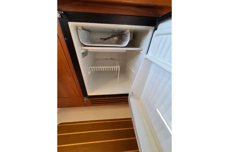 Slide: The Image of Open refrigerator inside 2001 Mainship 30 Pilot Rum Runner boat, wooden cabinetry visible. - 28