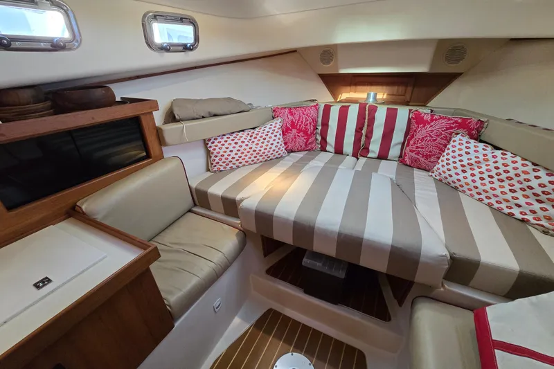 Slide: The Image of Cozy cabin interior of 2001 Mainship 30 Pilot Rum Runner with striped cushions and colorful pillows. - 32