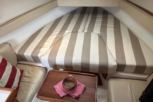 Slide: The Image of 2001 Mainship 30 Pilot Rum Runner cabin with striped bedding and wooden table. - 33