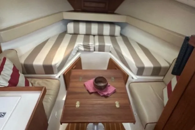 Slide: The Image of 2001 Mainship 30 Pilot Rum Runner cabin with striped cushions and wooden table. - 34