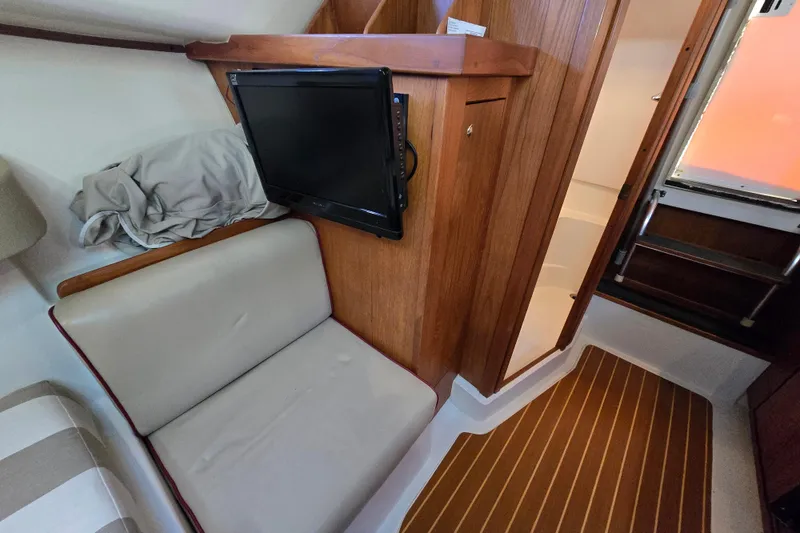 Slide: The Image of 2001 Mainship 30 Pilot Rum Runner cabin interior with seating, TV, and wooden accents. - 35