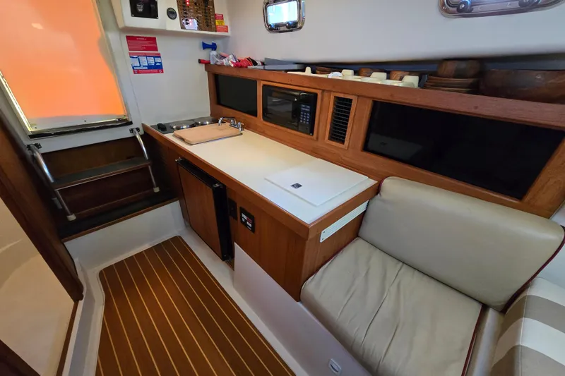 Slide: The Image of 2001 Mainship 30 Pilot Rum Runner cabin with kitchenette, seating, and wooden accents. - 36