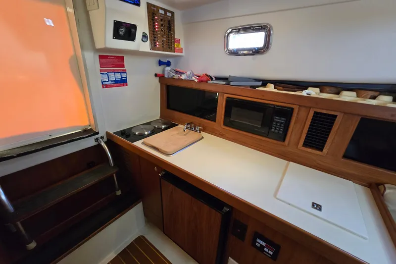 Slide: The Image of 2001 Mainship 30 Pilot Rum Runner galley with stove, microwave, and compact design. - 37