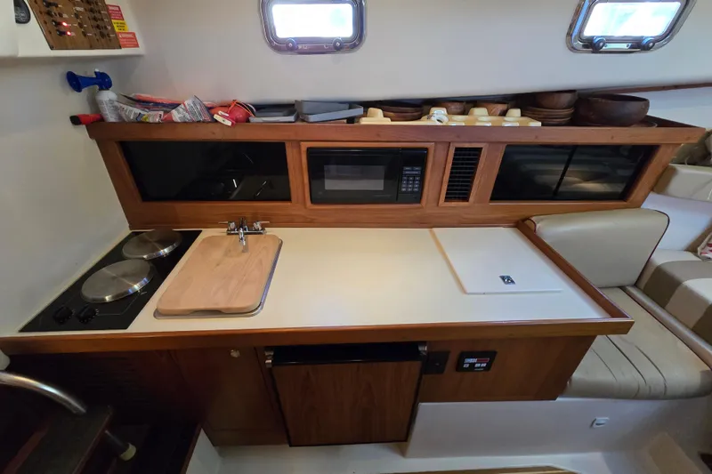 Slide: The Image of 2001 Mainship 30 Pilot Rum Runner galley with stove, sink, microwave, and storage. - 38