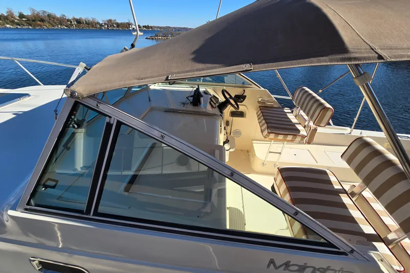 Slide: The Image of 2001 Mainship 30 PILOT boat with striped seating and canopy on a sunny day. - 40