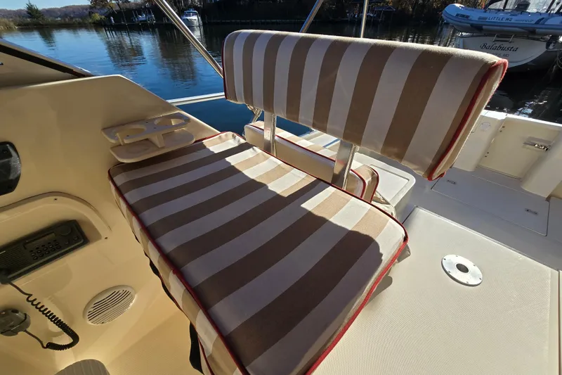 Slide: The Image of Striped seating on 2001 Mainship 30 Pilot Rum Runner boat, docked by calm waters. - 5
