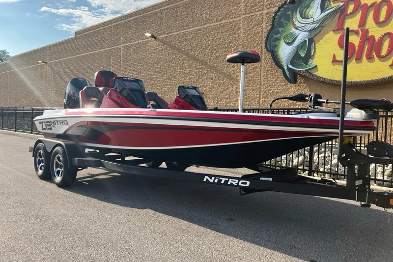 Slide: The Image of 2026 Nitro Z19 XL boat on trailer outside Pro Shop, featuring sleek red and white design. - 2