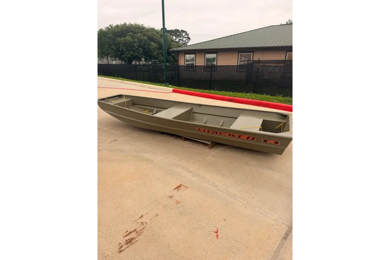 The Image of 2026 Tracker Grizzly 14 Jon boat on concrete surface, near a building. - 0