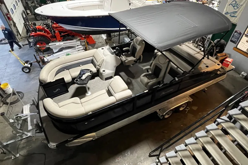 Slide: The Image of 2021 Barletta Cabrio 22UC pontoon boat with canopy, parked indoors on a trailer. - 5