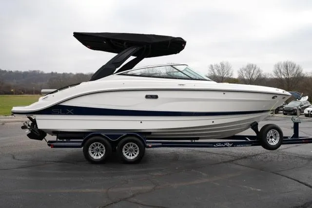 Slide: The Image of 2026 Sea Ray SLX 260 boat on trailer, white with black canopy, parked outdoors. - 11