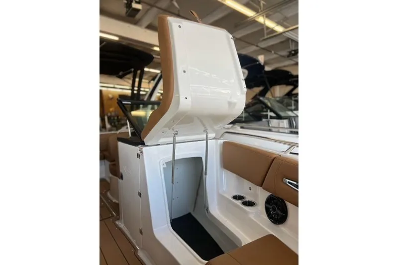 Slide: The Image of 2025 Chaparral 247 SSX boat interior with open storage compartment and tan seating. - 12