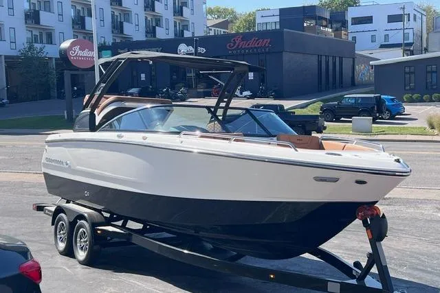 Slide: The Image of 2025 Chaparral 247 SSX boat on trailer in urban setting, near Indian Motorcycle shop. - 2