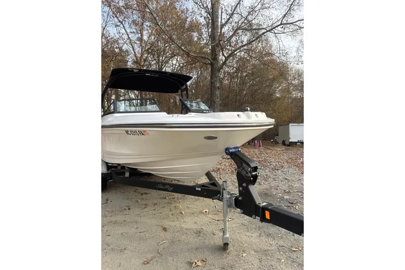 Slide: The Image of 2023 Sea Ray SPX 210 boat on trailer, parked outdoors with trees and sunset background. - 10