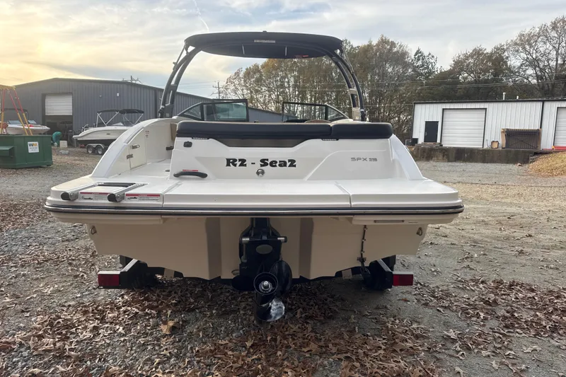 Slide: The Image of 2023 Sea Ray SPX 210 boat parked outdoors at sunset, rear view. - 16