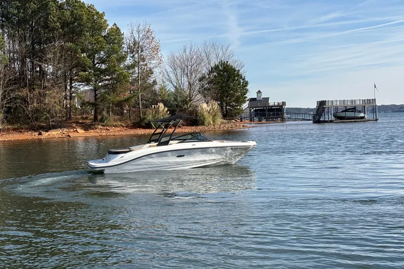 Slide: The Image of 2023 Sea Ray SPX 210 boat cruising on a serene lake with trees in the background. - 2
