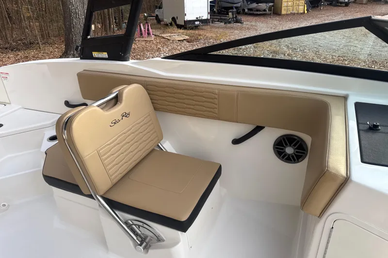 Slide: The Image of 2023 Sea Ray SPX 210 boat interior with tan seating, parked outdoors. - 26