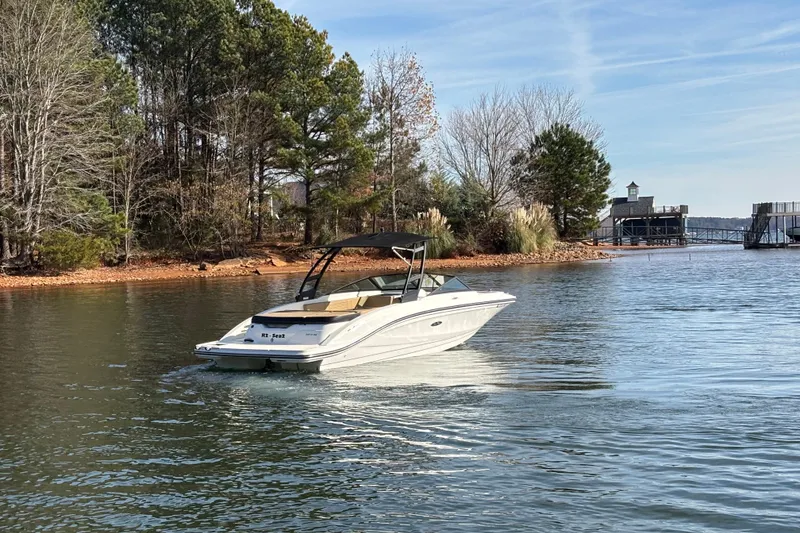 Slide: The Image of 2023 Sea Ray SPX 210 boat cruising on a serene lake near a wooded shoreline. - 3