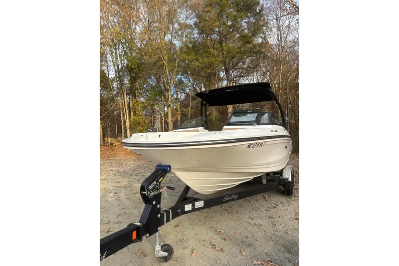 Slide: The Image of 2023 Sea Ray SPX 210 boat with tan seating and black canopy in wooded area. - 7