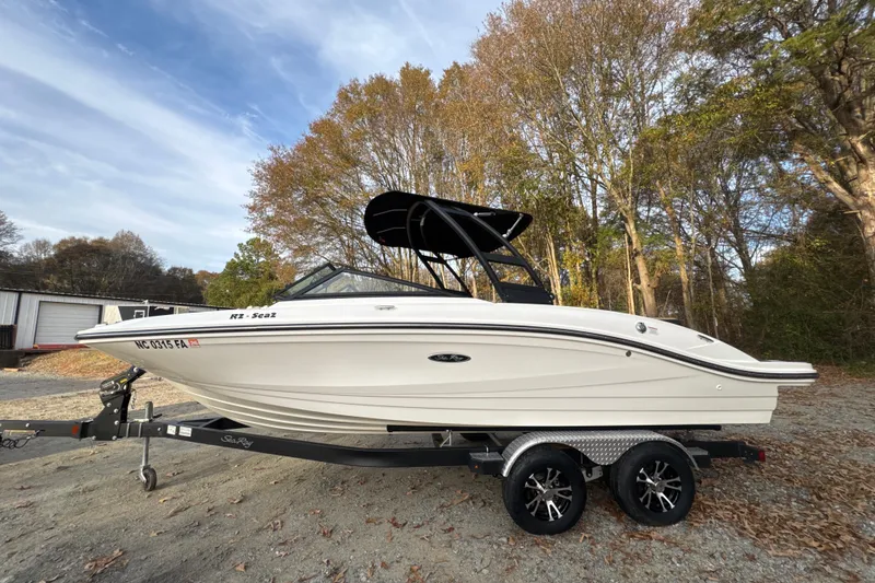 Slide: The Image of 2023 Sea Ray SPX 210 boat on trailer, parked in wooded area. - 8