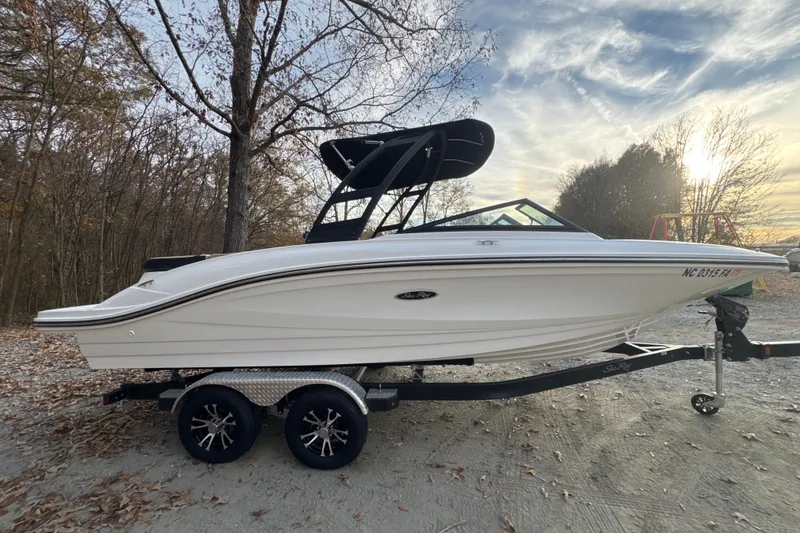 Slide: The Image of 2023 Sea Ray SPX 210 boat on trailer, parked outdoors with trees in background. - 9