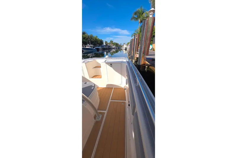 Slide: The Image of 2004 World Cat 330 TE boat interior with seating and storage, docked near waterfront homes. - 11
