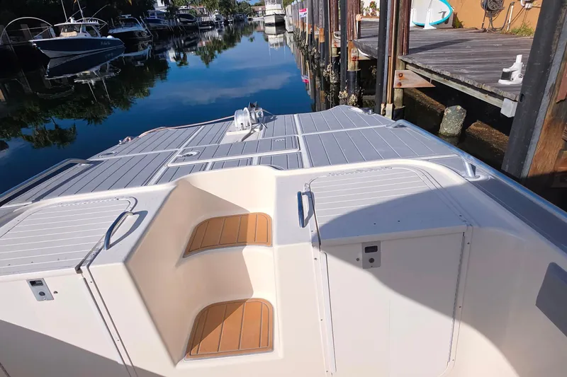 Slide: The Image of 2004 World Cat 330 TE boat interior with wooden deck, docked by palm trees. - 13