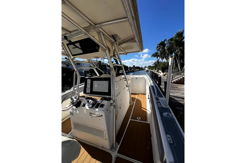 Slide: The Image of 2004 World Cat 330 TE boat interior with rod holders and console, docked under clear sky. - 6