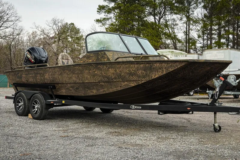Slide: The Image of 2026 G3 Sportsman 2100 boat with camouflage design on a trailer, parked outdoors. - 5