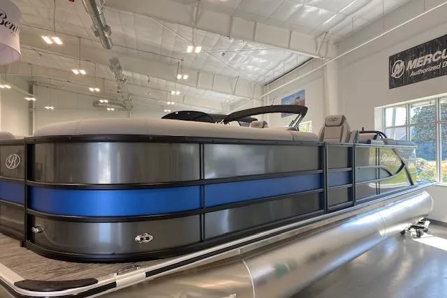 Slide: The Image of 2026 Bentley Pontoons Legacy 243 Navigator in showroom, sleek design with blue accents. - 3