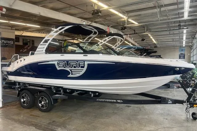 Slide: The Image of 2025 Chaparral 23 Surf boat displayed indoors on a trailer. - 1