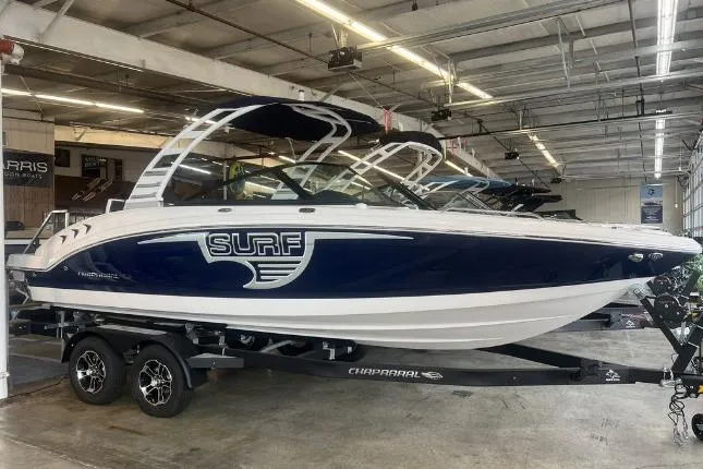 Slide: The Image of 2025 Chaparral 23 Surf boat in showroom, sleek design, blue and white color scheme. - 2