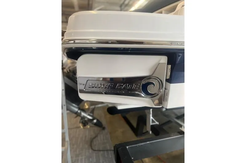 Slide: The Image of 2025 Chaparral 23 Surf boat detail with "Surf Gate" feature in a showroom. - 26