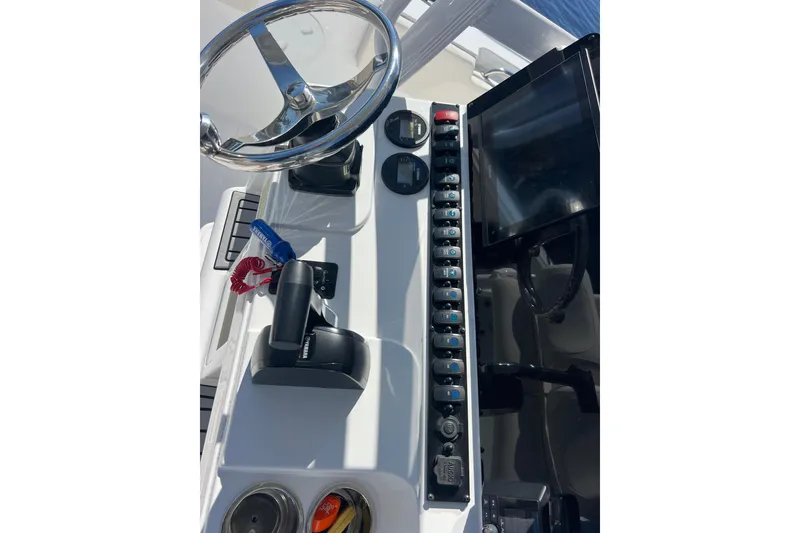 Slide: The Image of Control panel of a 2004 Sea Hunt Ultra 234 boat with steering wheel and switches. - 12